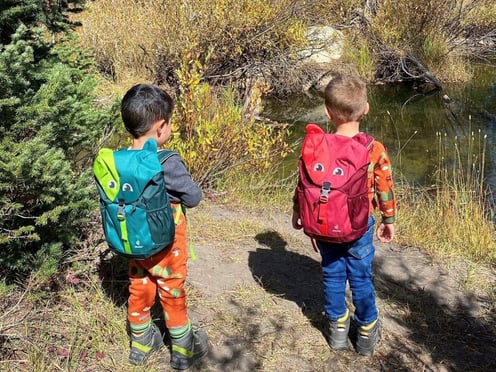 Two young boys wearing deuter Kikki backpacks by a river