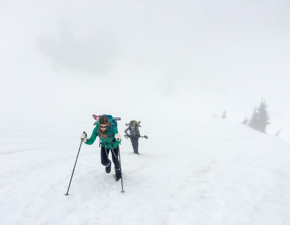 Two young mountaineers making their way through fog. 
